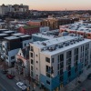 aerial view of building on a corner of two streets and a city in the background