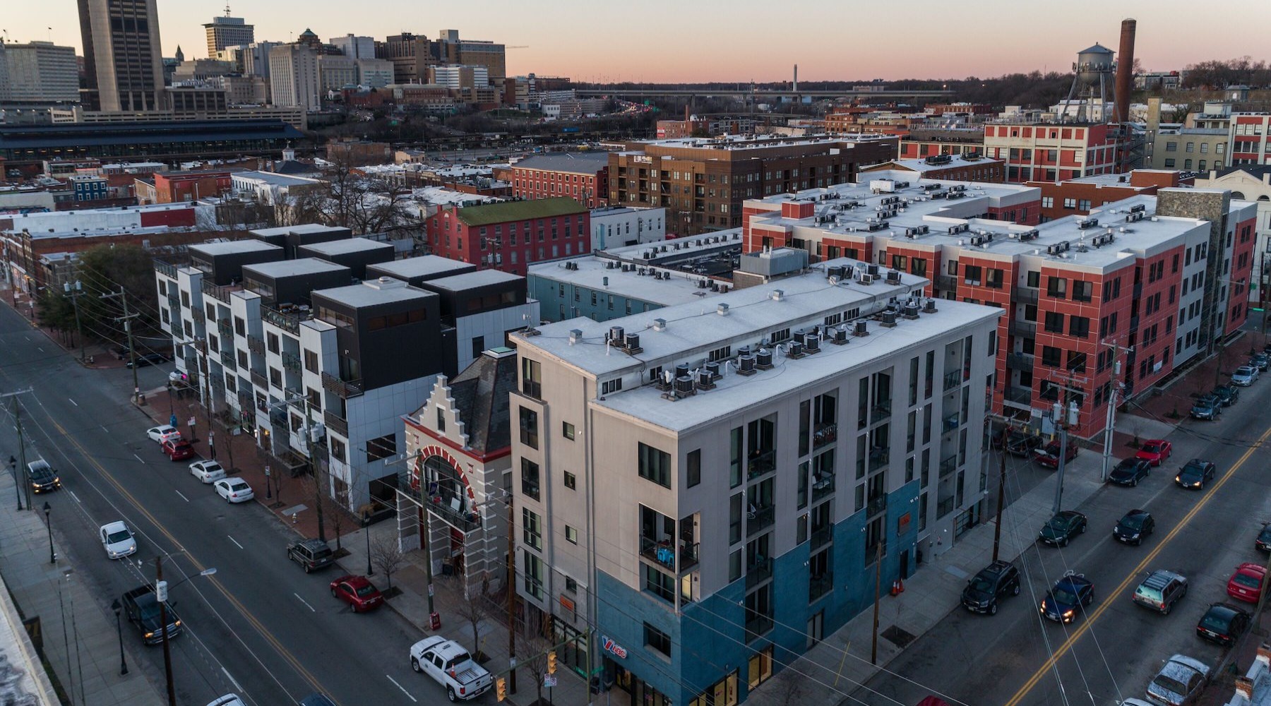 Close to the center of everything aerial view of building on a corner of two streets and a city in the background