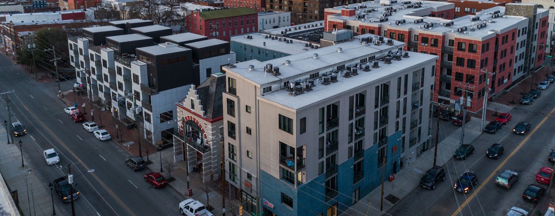 aerial view of building on a corner of two streets and a city in the background